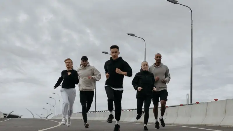 Grupo de runners corriendo juntos por una avenida urbana