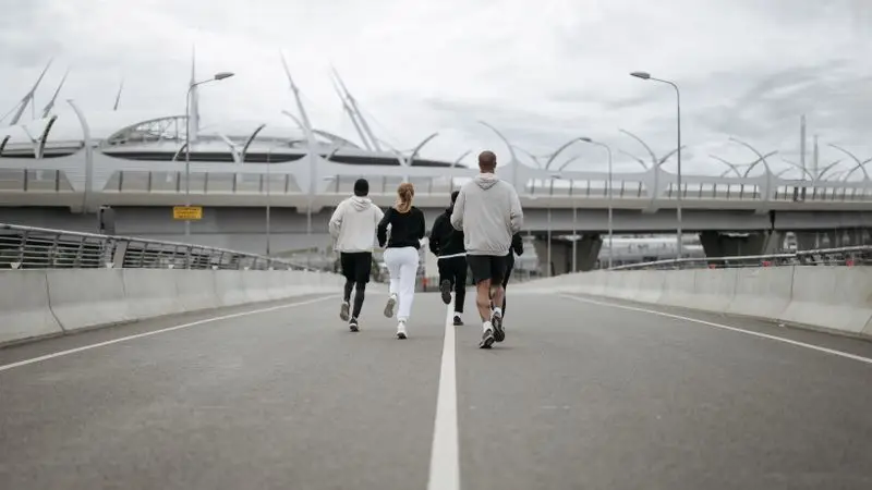 Grupo de corredores haciendo footing por un puente urbano moderno