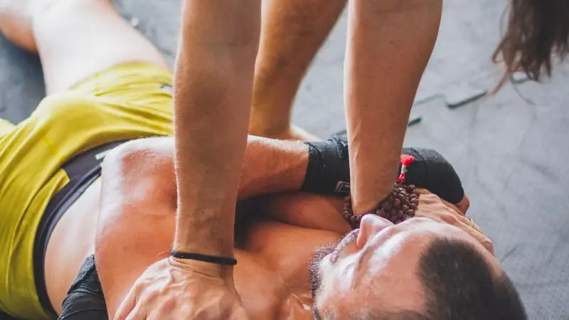 Entrenador ayudando a deportista con foam roller