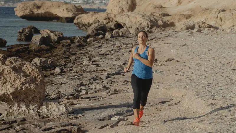 Mujer corriendo por la playa junto al mar