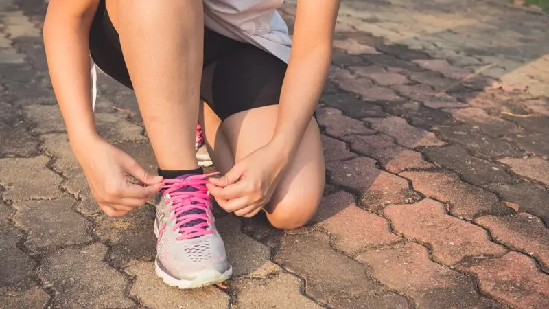 Mujer atándose las zapatillas de running en una pista de atletismo