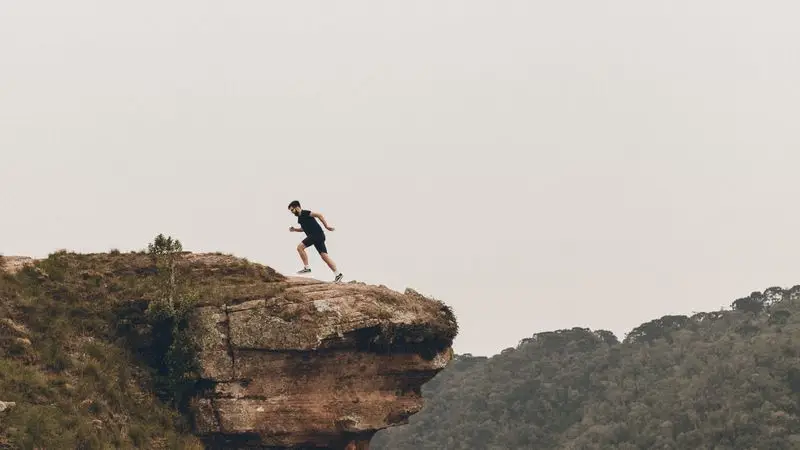 Trail runner corriendo por el borde de un acantilado en la montana
