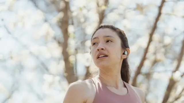 Imagen ambiental: corredora con un auricular inal&aacute;mbrico en el o&iacute;do; no corresponde al modelo analizado