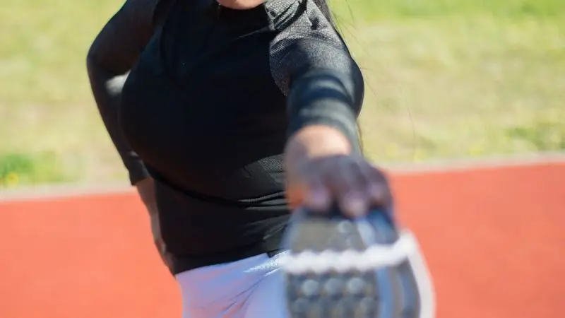 Mujer estirando las piernas en un parque después de correr