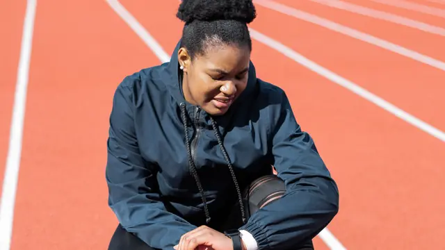 Imagen ambiental: deportista consultando su reloj sentada en una pista de atletismo; no corresponde a ning&uacute;n modelo analizado