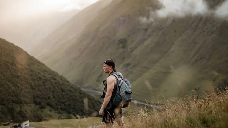 Hombre con mochila de trail recorriendo colinas de montana al amanecer