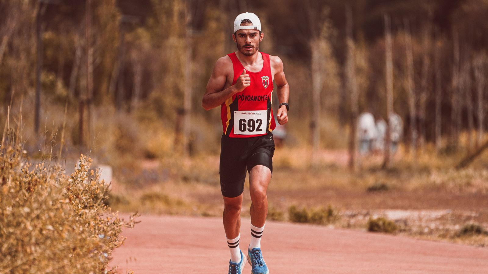 Corredor entrenando en carretera con dorsal, preparándose para una media maratón